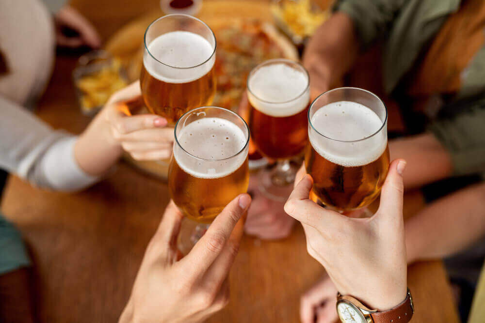 4명의 사람이 맥주가 든 잔을 들고 건배 하는 모습